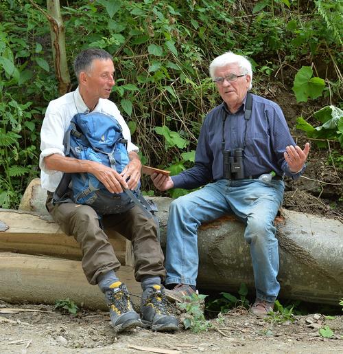 zwei Herren im Gespräch auf einem Baumstamm